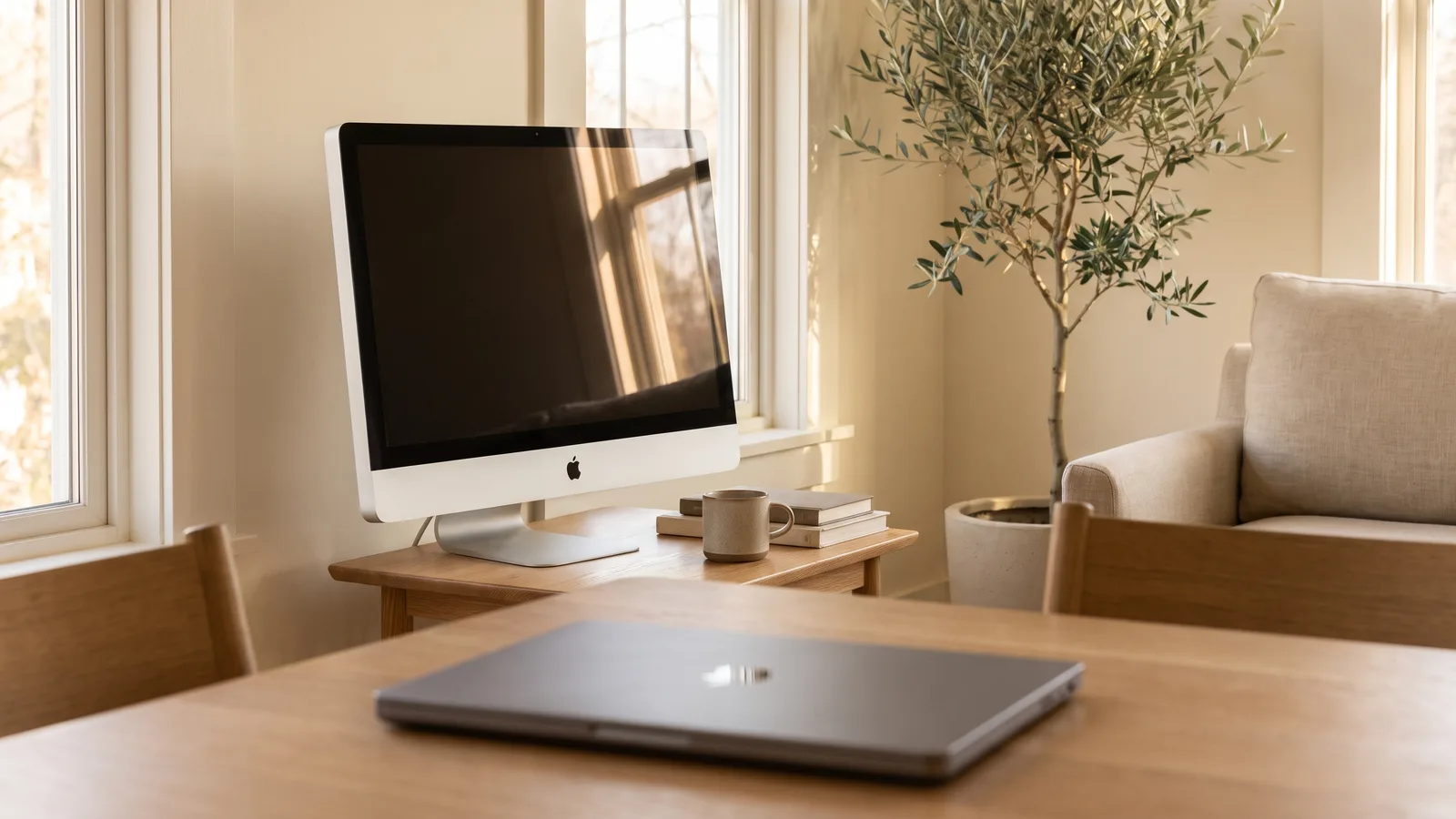 A silver 27-inch iMac switched off on a side table, with a newer MacBook in front.